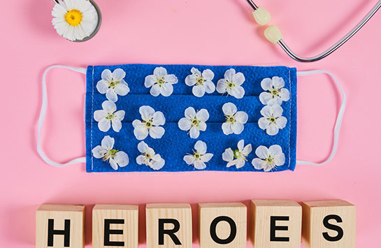 Stethoscope, flowers and medical protective mask with wooden cubes. Text heroes for gratitude to medical personnel and doctors