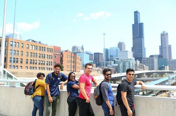 Students stand on the bridge with the city skyline in the background