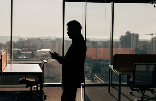 The silhouette of a person standing in an empty office