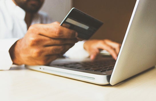 A person holding a credit card and making an online payment